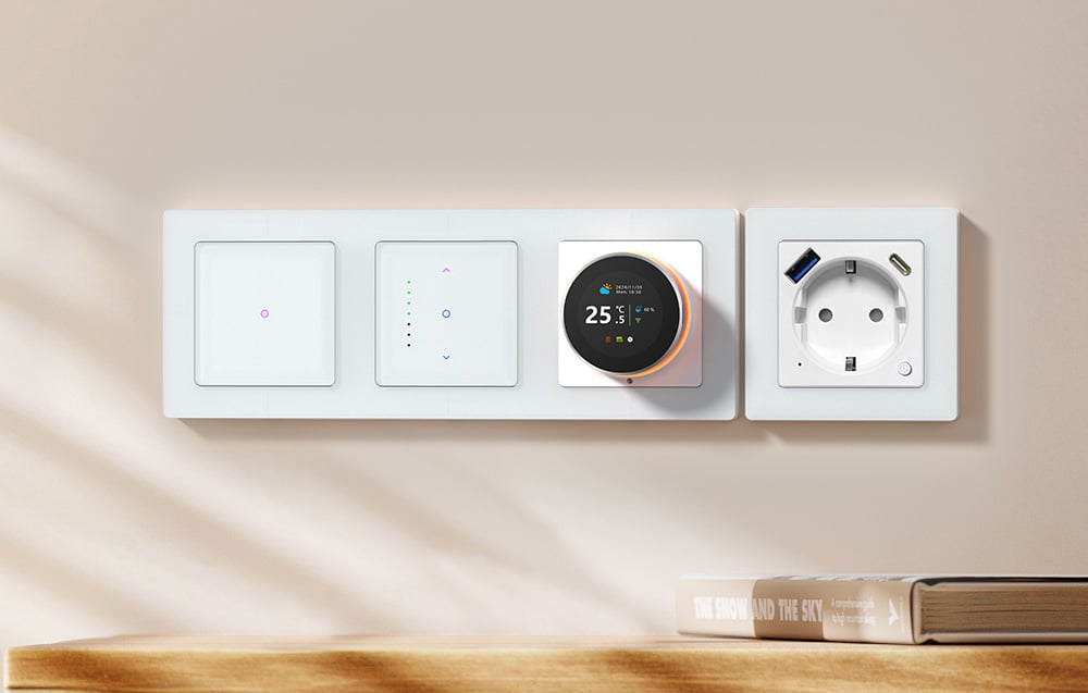 Touch light switches, a smart thermostat and an outlet on a pale wall above a bookshelf
