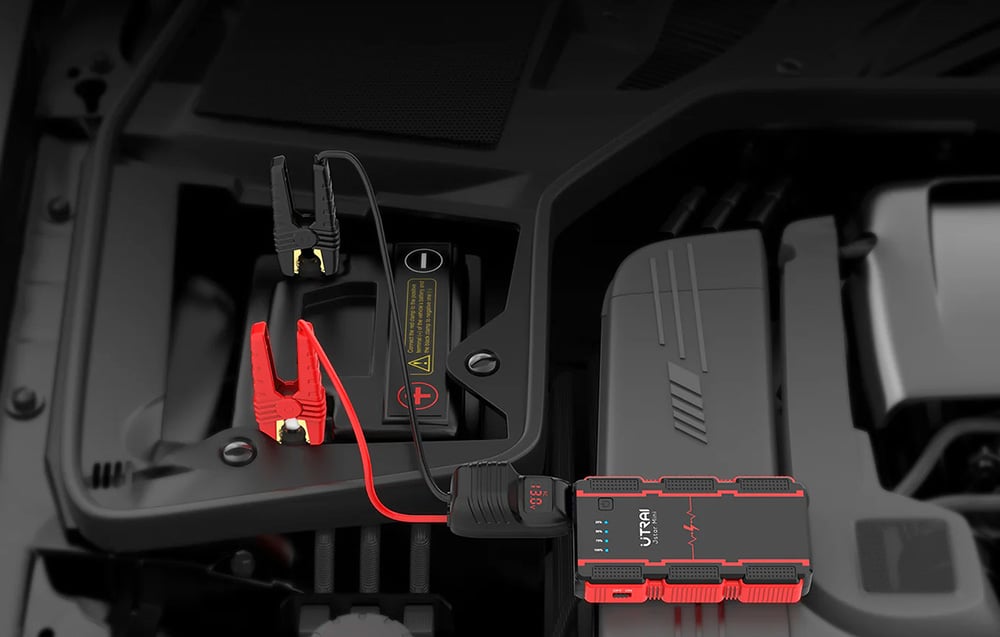 The jump starter is connected to the car battery with two clamps, one red and one black.