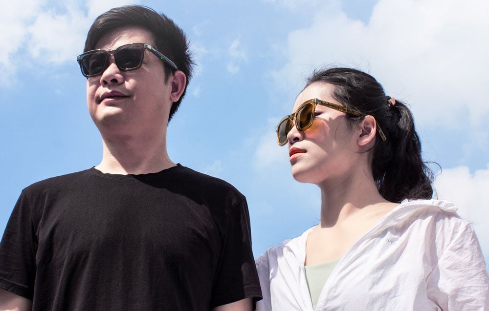 A man and a woman standing next to each other outside, both wearing different models of smart sunglasses.