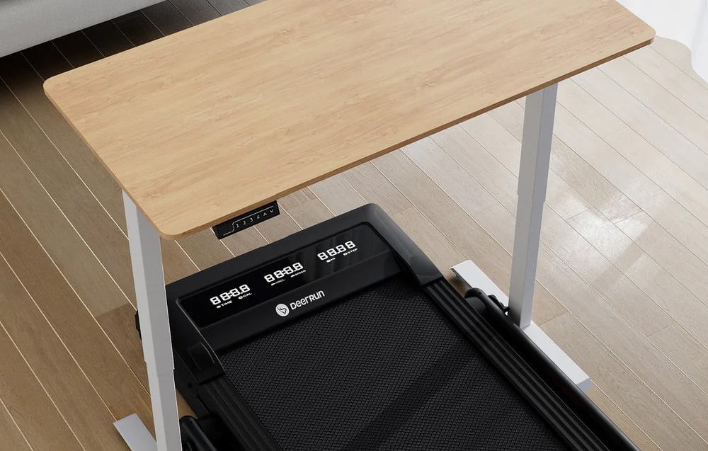 Black DeerRun treadmill with multiple displays under a wooden desk in a bright room