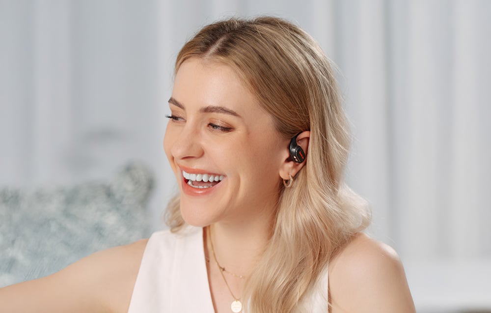 Smiling woman in bright interior wearing black in-ear headphones