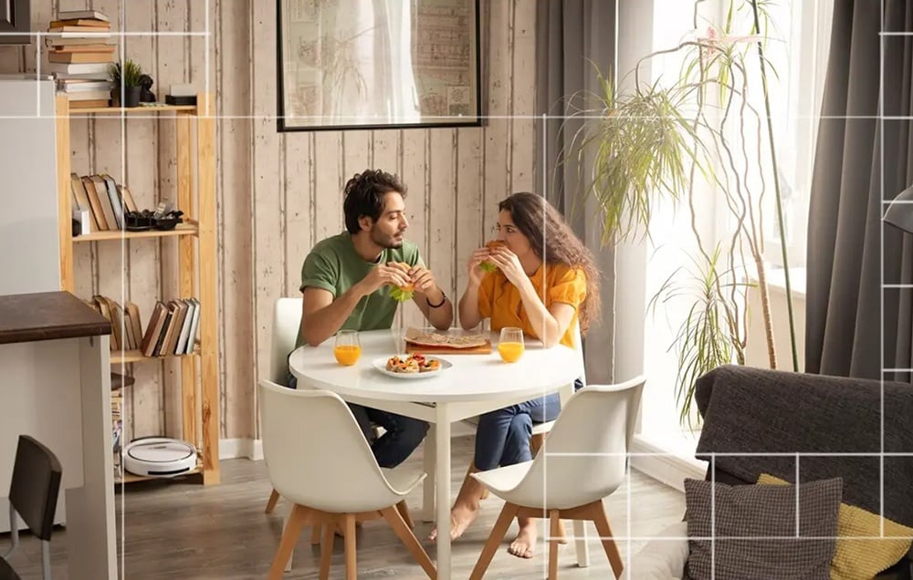 A couple sitting at a table eating a meal, with a grid of white lines superimposed on the image