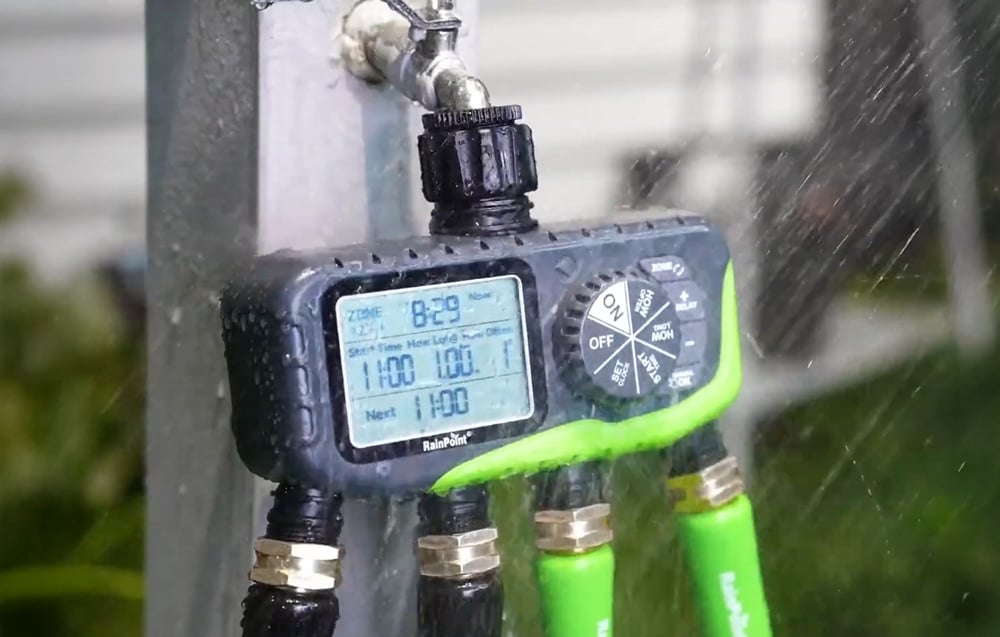 RainPoint 4-zone irrigation controller connected to an outdoor faucet during heavy rainfall