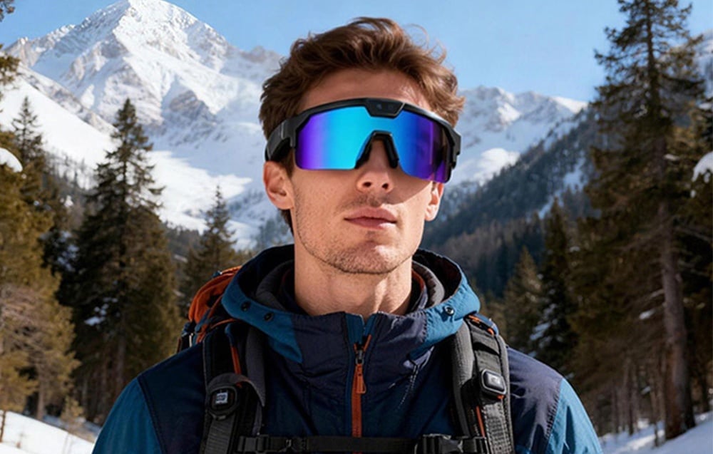 A man in a jacket with a backpack and AI glasses against a winter mountain landscape