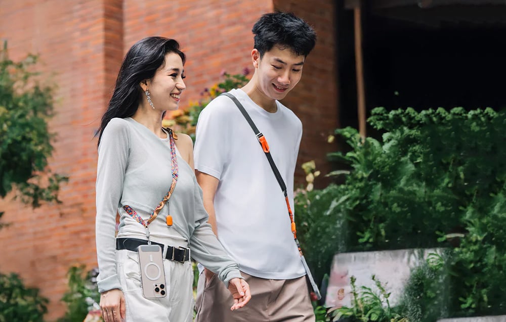 A woman and a man are walking through the city, they have PGYTECH straps hanging on their shoulders