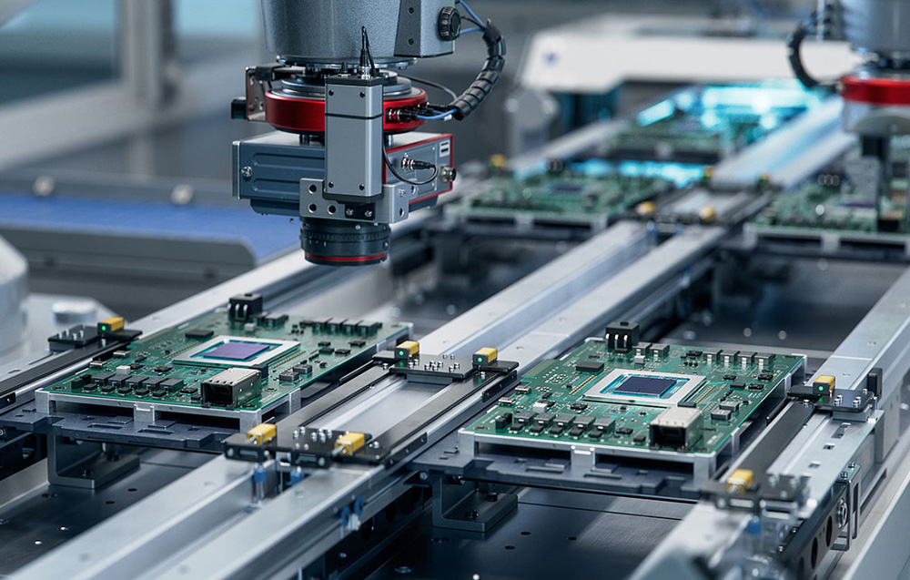 An automated production line in a factory where robotic arms assemble precision electronics and motherboards.