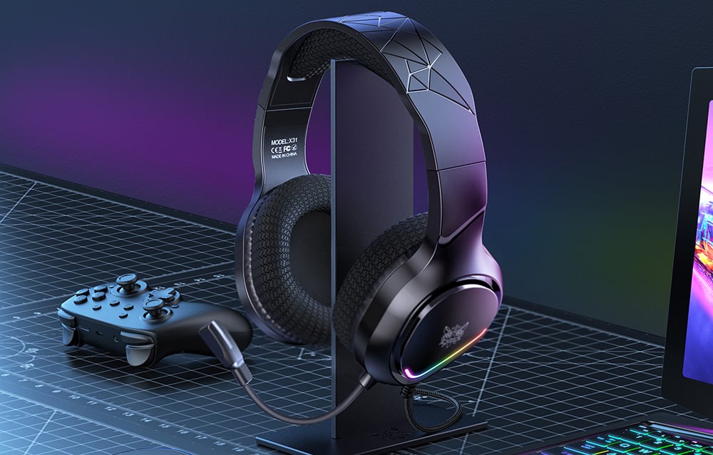 Black over-ear headphones on a dedicated stand lie on the desk next to the laptop and gaming pad