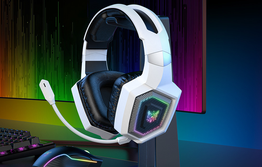 White gaming headphones hanging on a bracket next to a monitor, keyboard and mouse