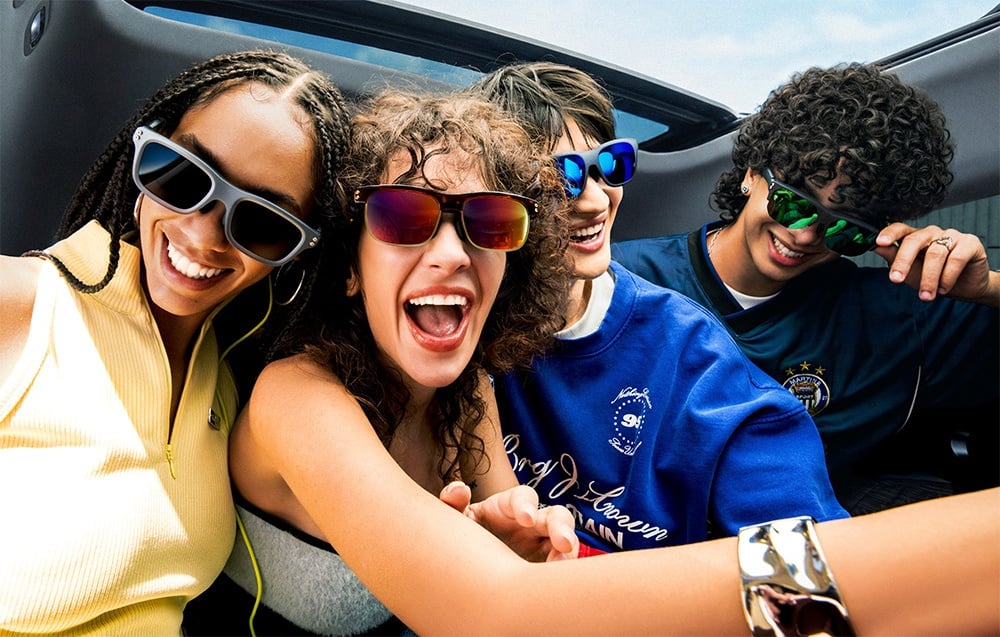 A group of four people wearing glasses inside a convertible