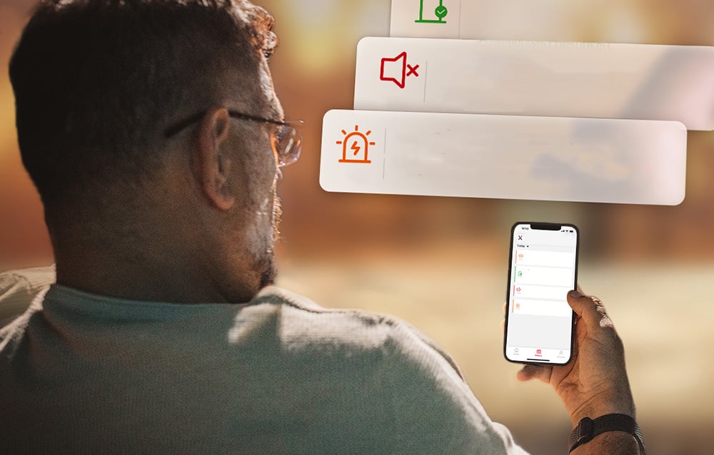 A man looks at his smartphone screen showing a list of notifications regarding the alarm and sound muting