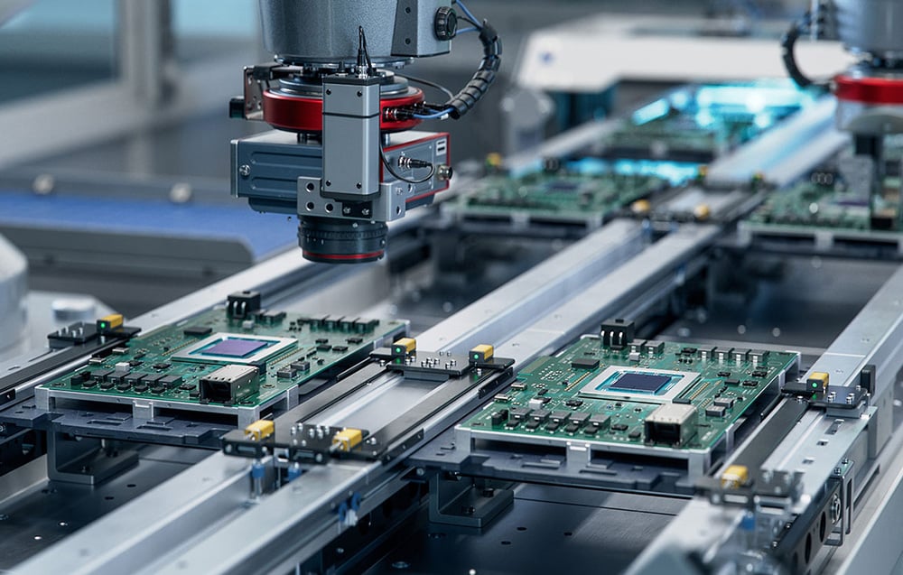 An automated production line in a factory where robotic arms assemble precision electronics and motherboards.