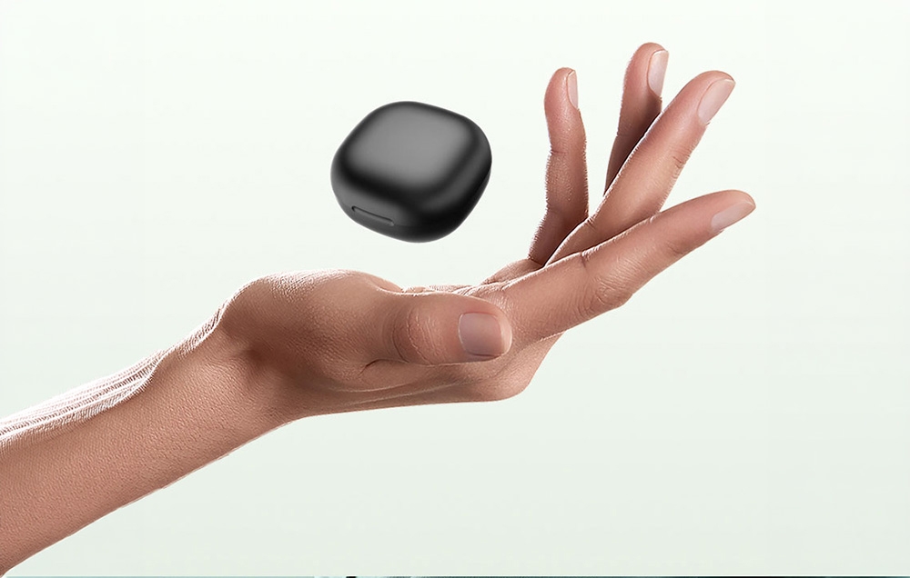 A raised hand with a closed black charging case for a smart ring hovering above it