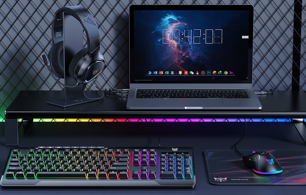 Onikuma gaming set: keyboard, mouse, mouse pad, headphones, and stand are on the desk next to the laptop