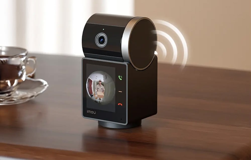 Indoor monitor displaying the video doorbell feed and green and red handset icons, standing on a wooden countertop