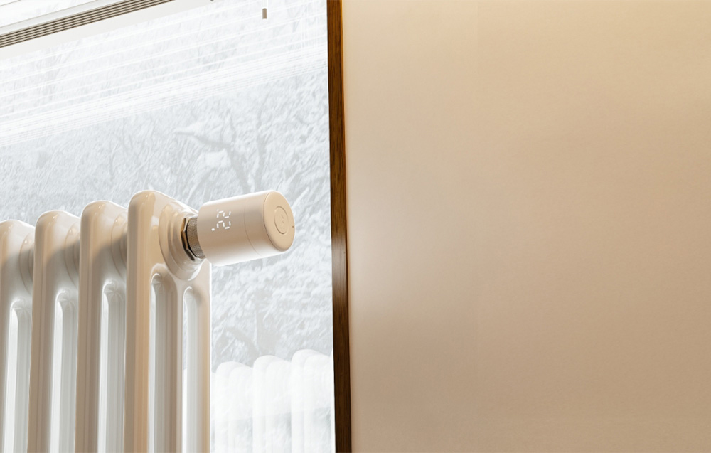 Thermostat radiator with snow falling outside the window