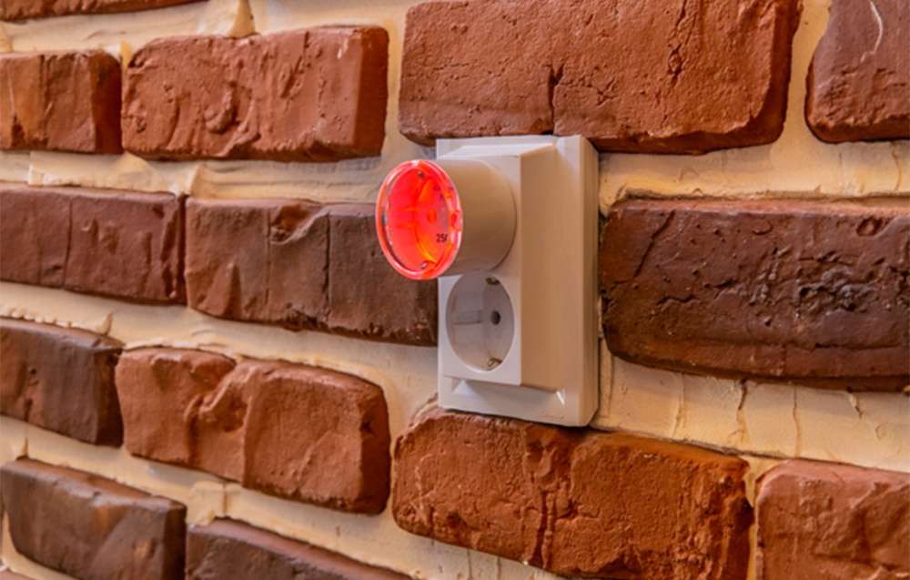 Red backlight of Shelly Plug S mounted on a brick wall