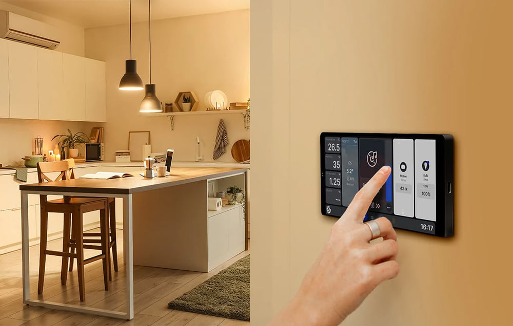 Close-up of a user's hand operating the Shelly X2i panel against the backdrop of a modern kitchen with an island.
