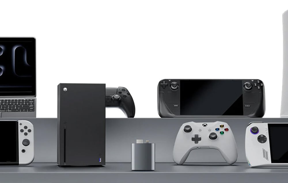 The adapter placed against a background of various gaming and multimedia devices, including consoles, controllers, laptop and handhelds.