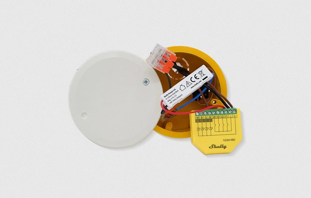 Top view of the connected Shelly unit in an open electrical box against a bright background