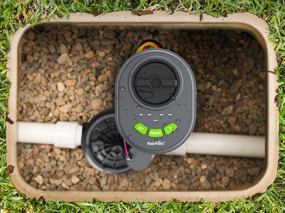 RainPoint controller in a small valve box filled with pebbles, top view.