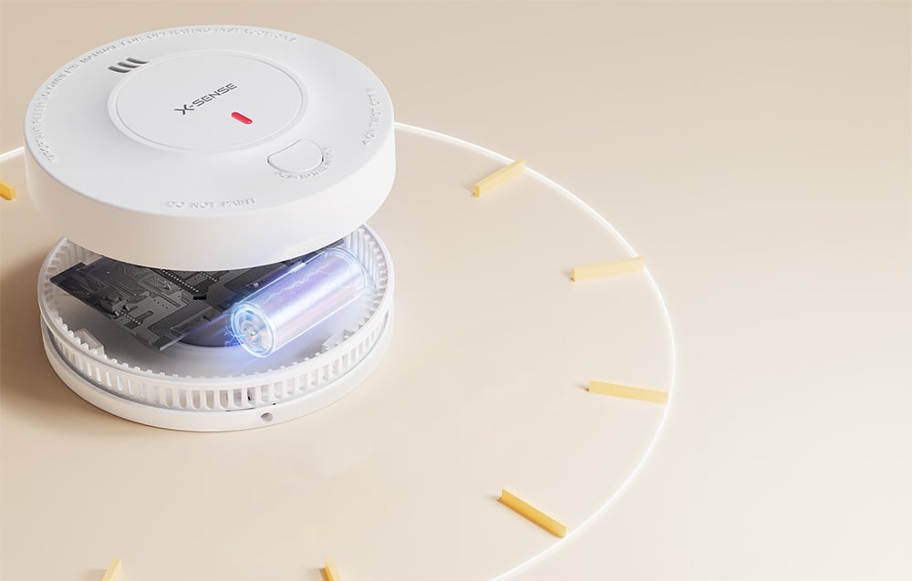 Open X-Sense smoke detector with visible battery and circuit board