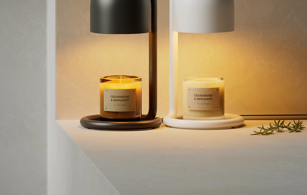 Two candle warmers—one black and one white—warming Cedarwood & Bergamot scented candles in glass containers, placed on a light-colored shelf against the wall.