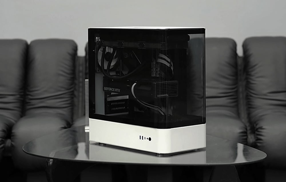 White-black computer case on dark table, black couch in the background