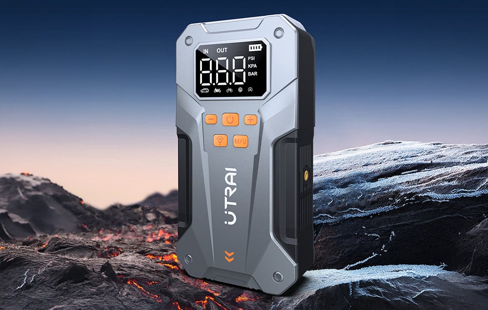 A car jump starter positioned vertically against a rugged, mountainous landscape under an evening sky.