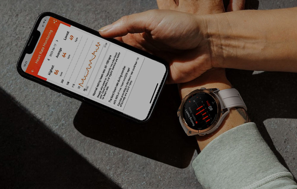 A smartphone with a heart rate monitoring app held above the wrist, which is wearing a light-colored smartwatch