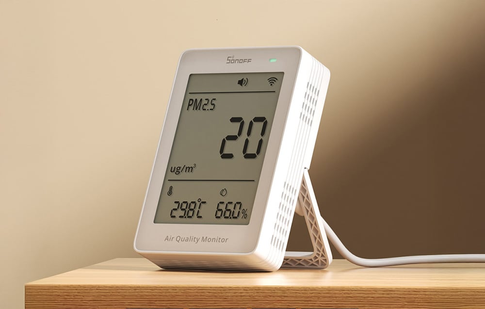 Sonoff air quality meter with LCD display on a wooden shelf