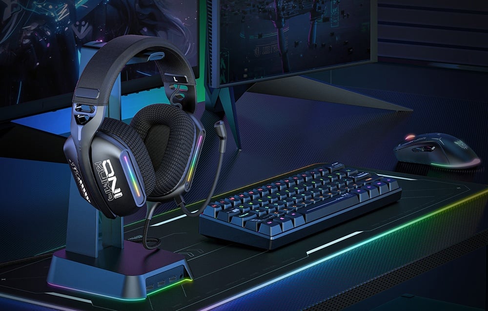 Headphones on a stand next to a gaming keyboard and mouse with RGB backlighting on a desk