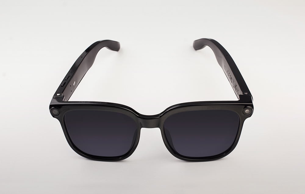 Front view of black glasses with dark lenses and thick frames integrated with a camera.