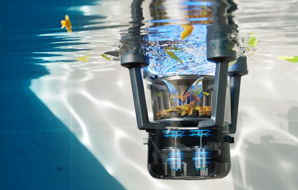 The floating robot floats on the water’s surface with a visible transparent basket full of collected leaves and debris