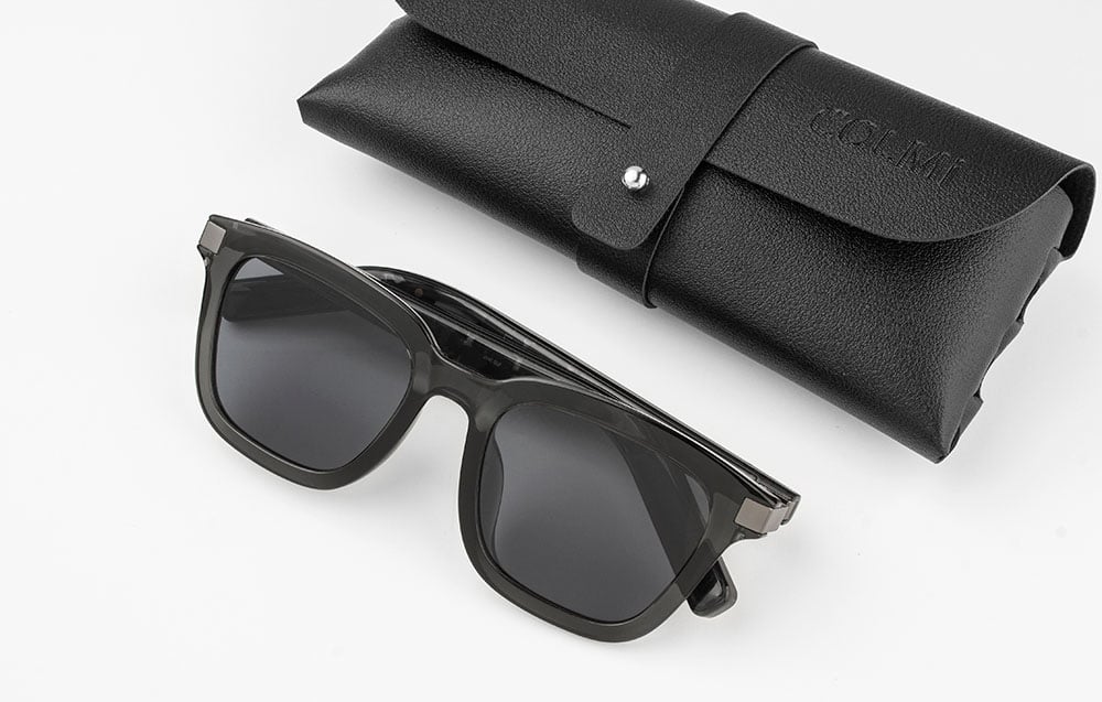 Black glasses and leather case on a gray background