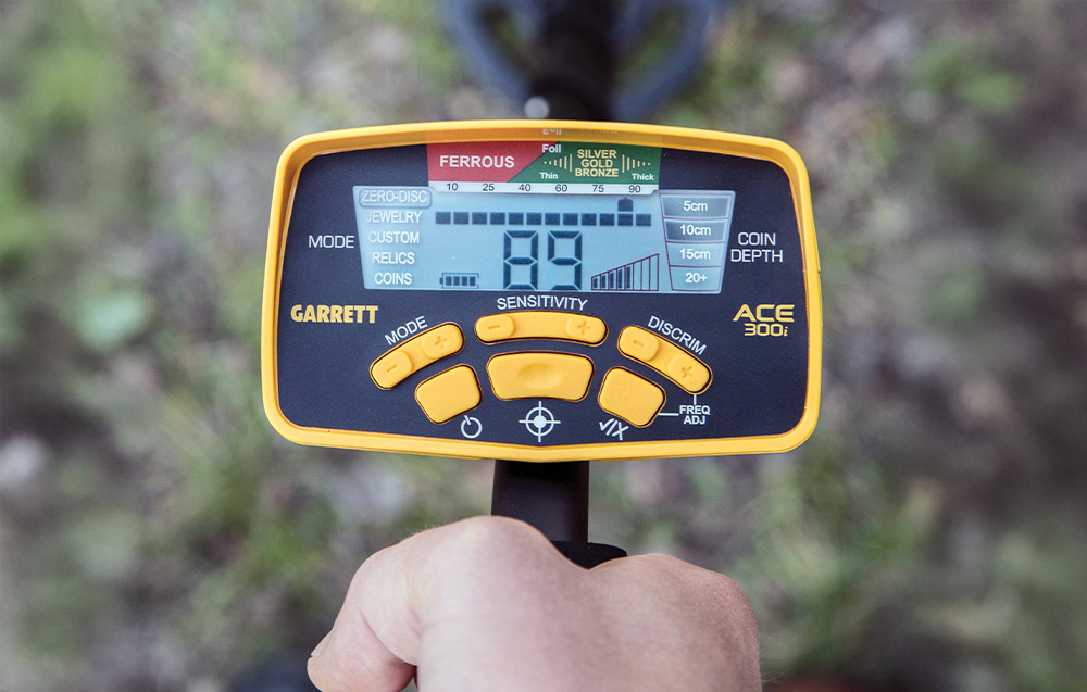 Close-up of the control panel of the Garrett ACE 300i metal detector with display and buttons.