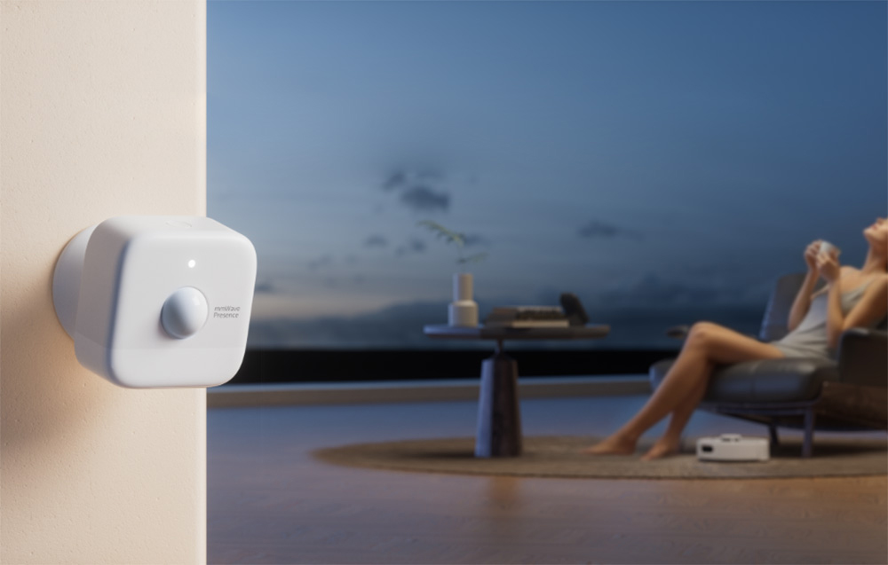A close-up of a motion sensor mounted in the corner of a wall in a modern living room.