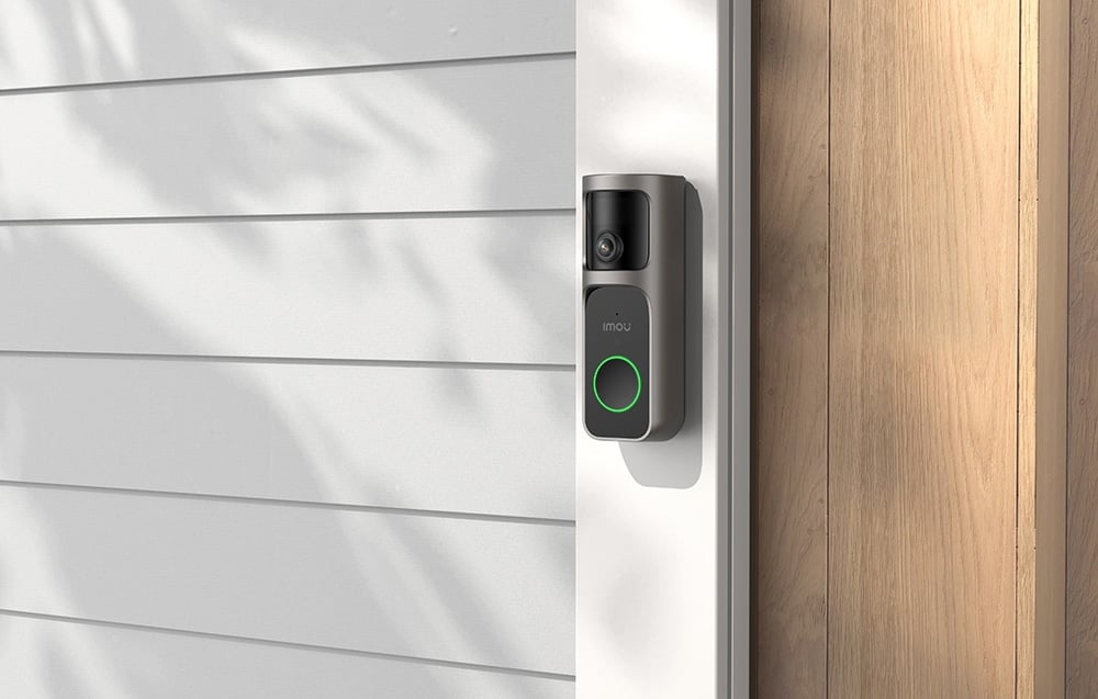 Imou video doorbell with a black panel and green button backlight, mounted on a white door frame