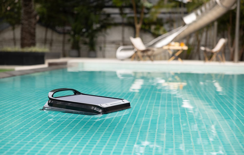 Wybot F1 robot floating in a pool next to a terrace with sun loungers