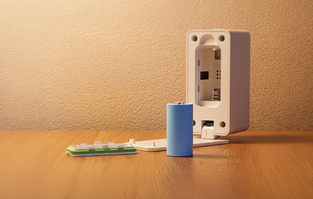 Smart presence sensor lying on a wooden table with the battery removed