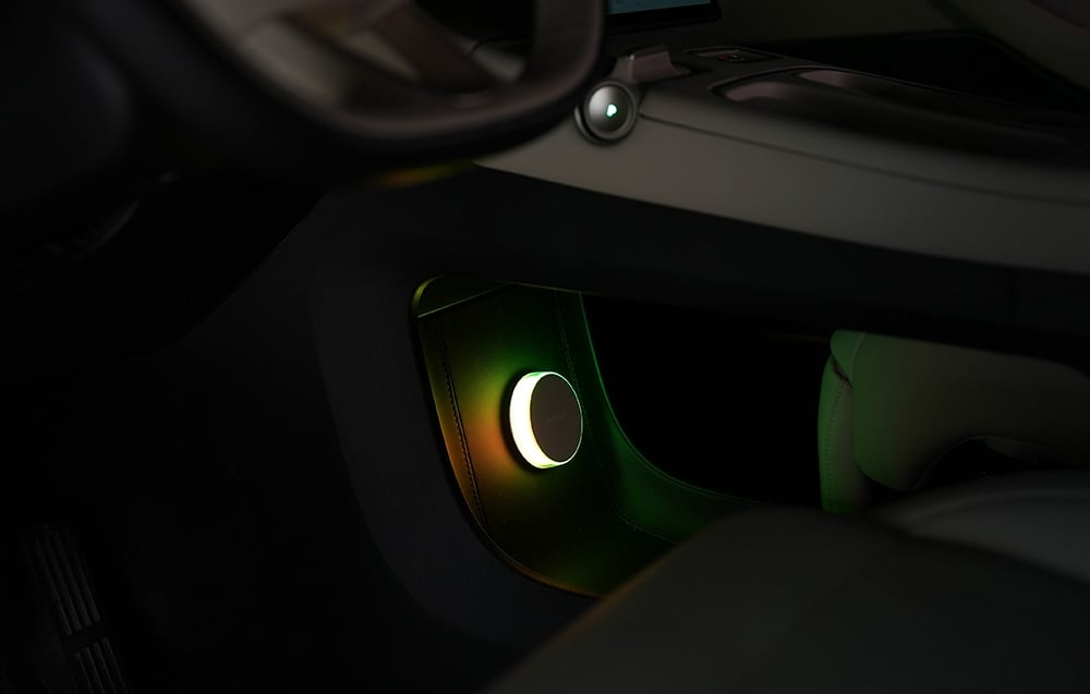 Yeelight Vega bedside lamp mounted on the bottom of the car dashboard, illuminated with green-yellow light.