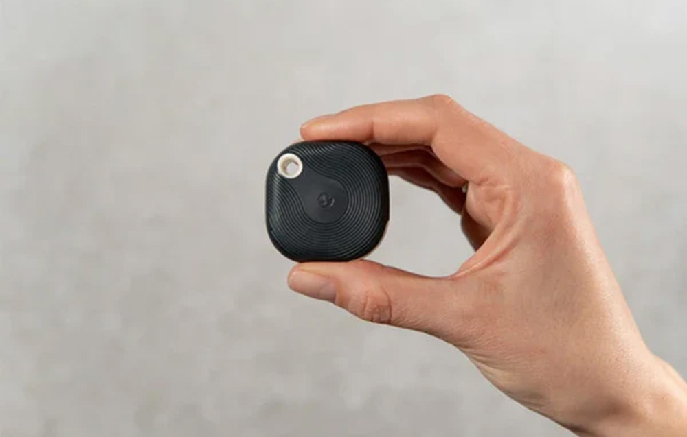 Black scene activation button held in hand on a gray background