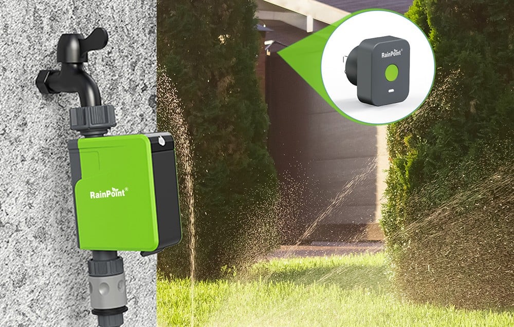 RainPoint irrigation controller mounted to a gray wall, with an irrigated garden in the background.