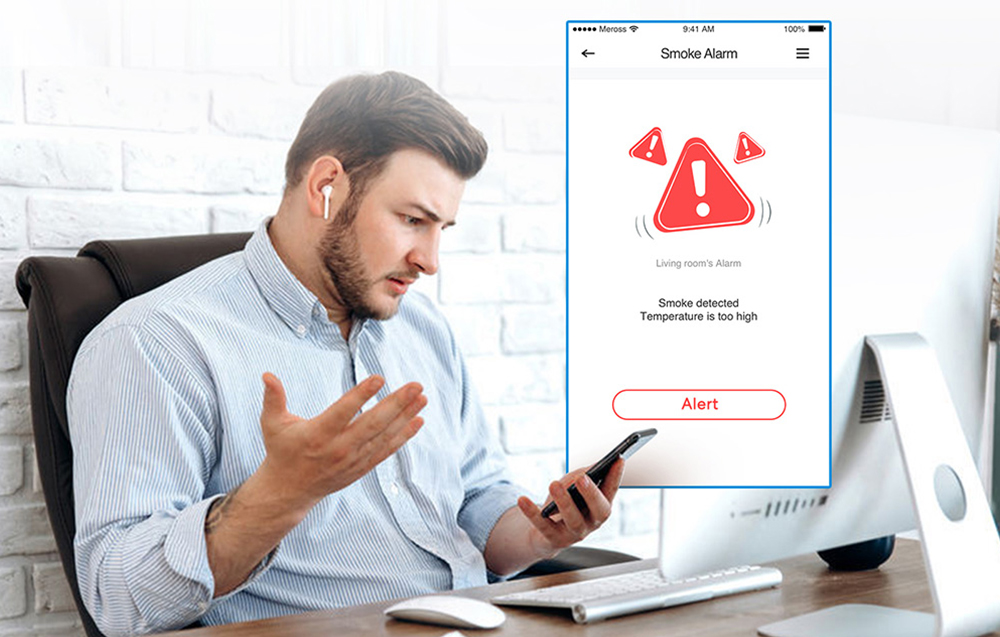 A man at his desk receiving a smoke detection alert on his smartphone from the detector app