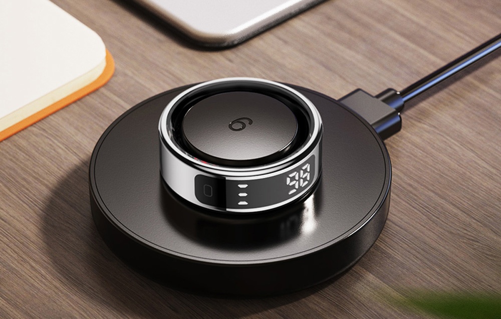 Smartring with display in charging base on wooden table.