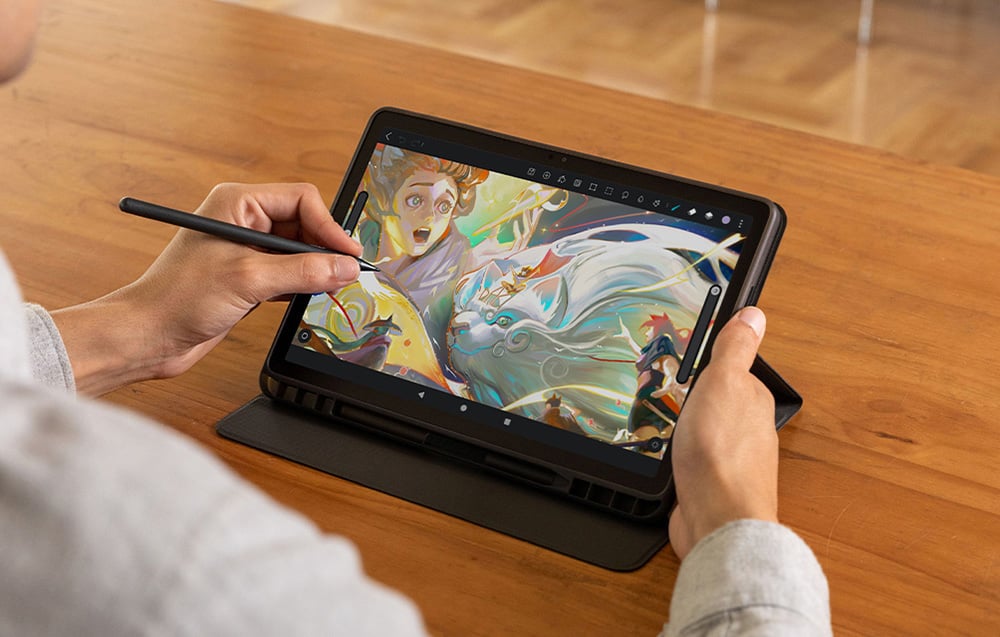 Hands drawing a colorful fantasy illustration with characters on a tablet with a stylus, top view