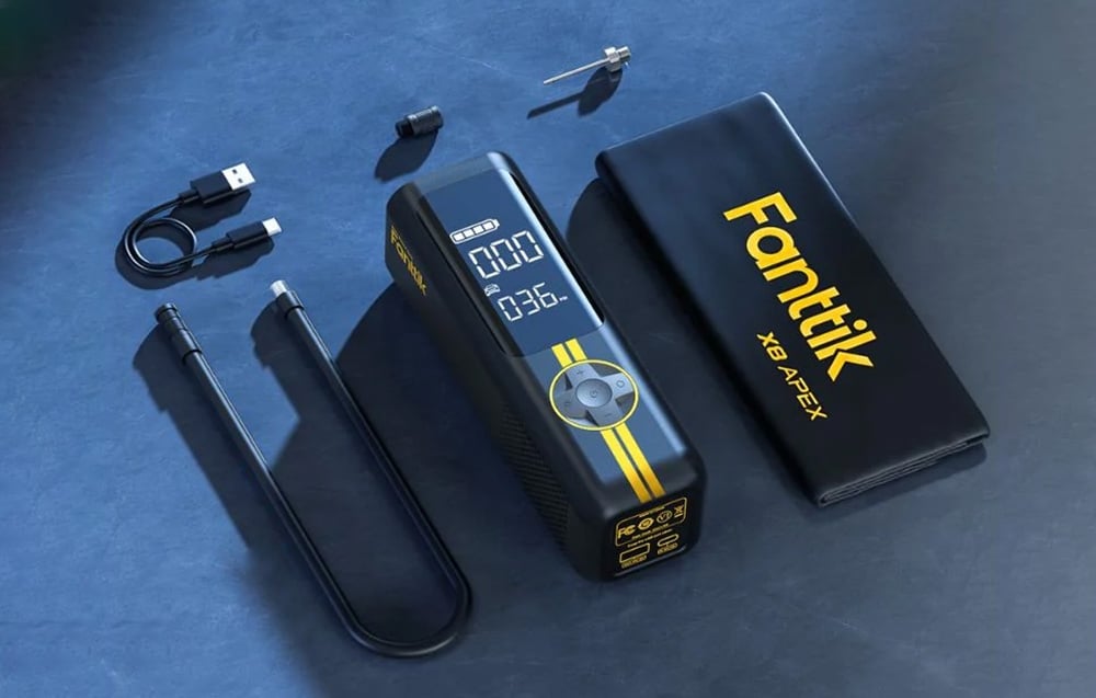 The Fanttik mini compressor with accessories lies on a dark blue ground.