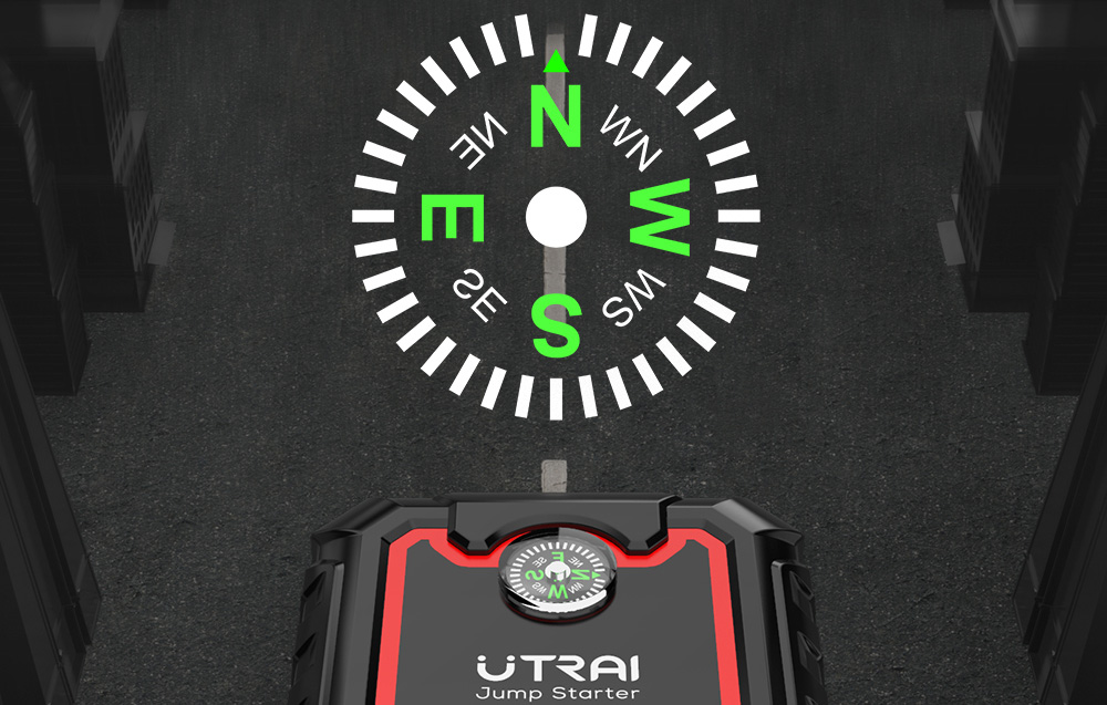 A close-up of the small compass built into the Utrai jump starter’s housing, set against the backdrop of an asphalt road.