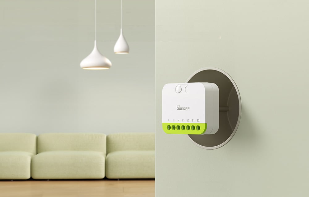 Sonoff switch mounted in the wall of the living room with the sofa and modern lighting visible