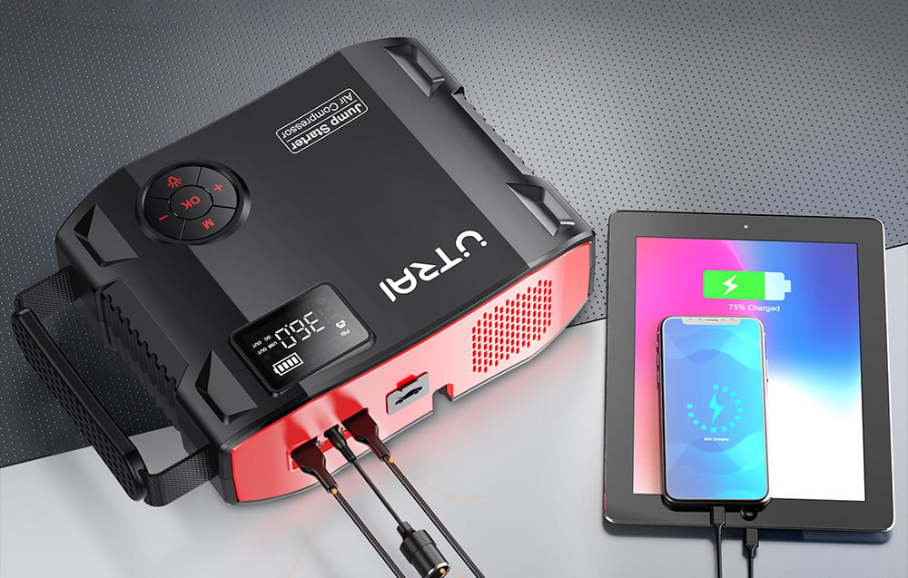 The jump starter simultaneously charges a smartphone and a tablet using cables connected to the ports.