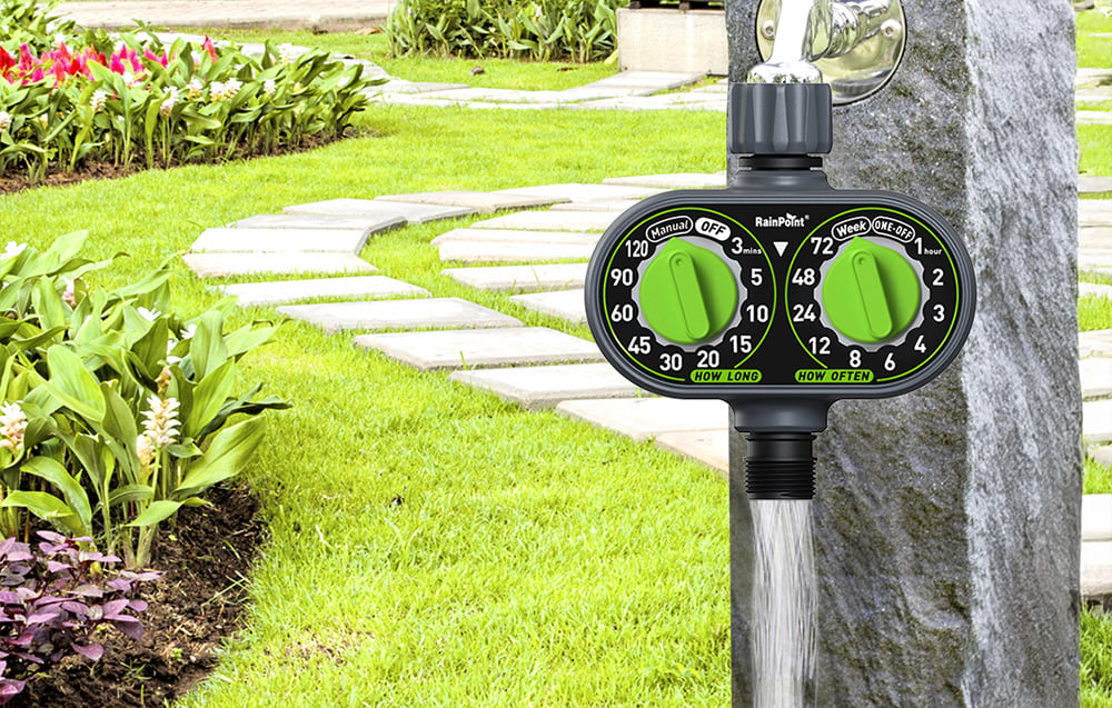 View of the RainPoint controller mounted on a stone post, through which a stream of water flows into the garden